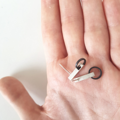 Handmade Minimalist Patina Stud Earrings in Sterling Silver is shown on the palm.