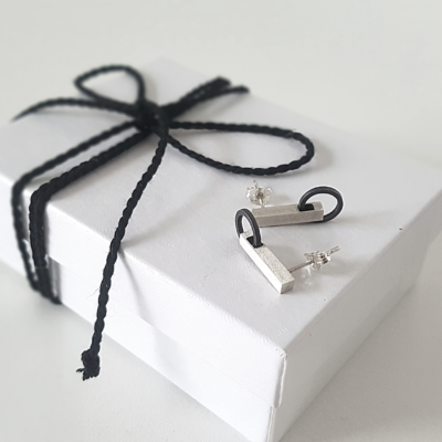 Hand-carved Minimalist Silver Patina Stud Earrings is shown on the white paper gift box tied with black cotton string.