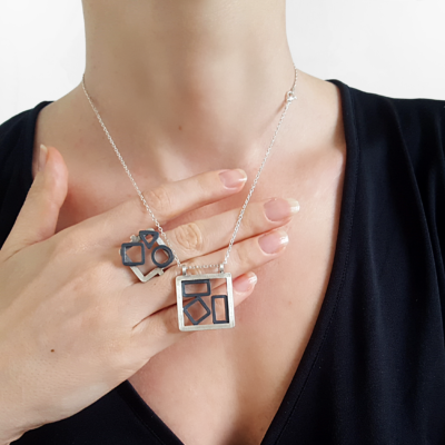Handcrafted Geometric Patina Sterling Silver pendant is worn on the lady.
