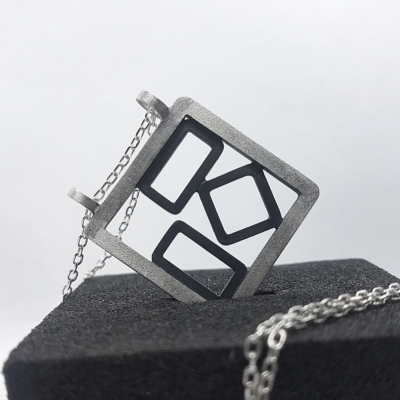 Hand-carved Patina Silver Pendant Necklace is displayed on the black sponge.