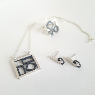 Handmade Oxidised Silver Set of jewellery is shown on the white surface.