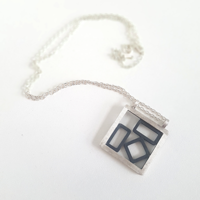 Hand-carved Patina Silver Pendant Necklace is displayed on the white surface.