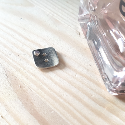 Artisan Custom Minimalist Silver Cubic Zirconia Apparel Button is placed on the wooden surface.