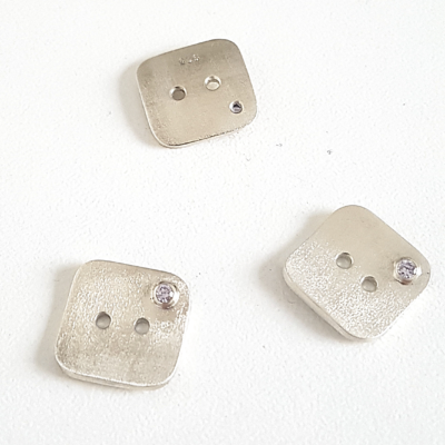 Artisan Custom Minimalist Silver CZ Apparel 3 Buttons are placed on the white surface.