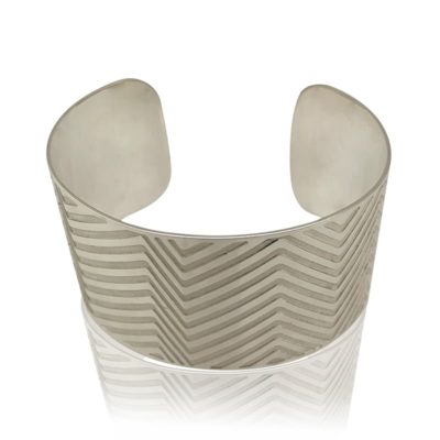 Wide Silver Oval Cuff With Etched Lines Laying Flat on a White Background