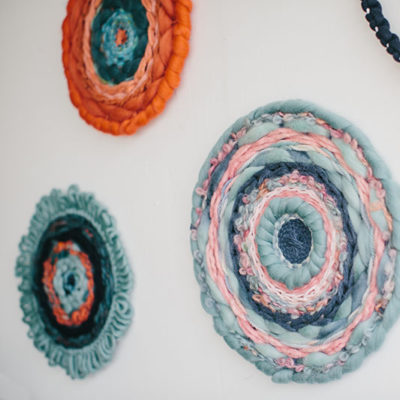 Cassandra Sabo’s ‘West Coast 9’ woven circular textile wall-hanging from her West Coast Collection hung on the wall with multiple artworks from this collection