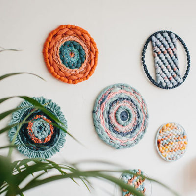 Cassandra Sabo’s ‘West Coast 9’ woven circular textile wall-hanging from her West Coast Collection hung on the wall with multiple artworks