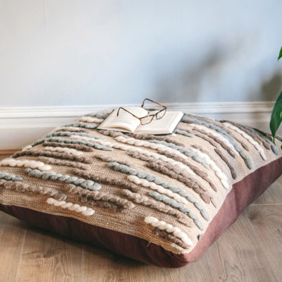 Handwoven 'Caterpillar' cushion featuring Merino wool by Cassandra Sabo styled with a book and glasses