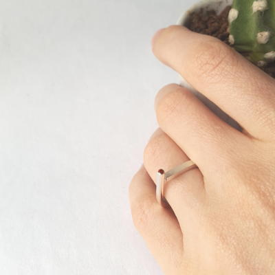 Contemporary sterling silver open ring with a gem is shown on the 4th finger of the palm.