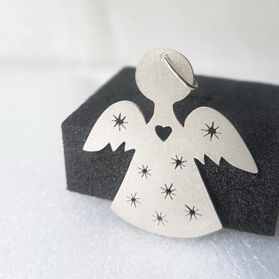 Silver Angel-Shaped Hanging Keepsake standing next to a black sponge.