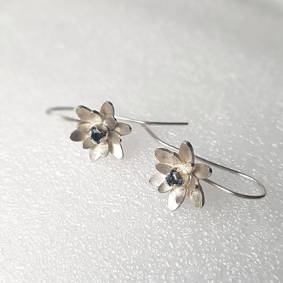 Handmade silver earrings with topaz on a white surface.