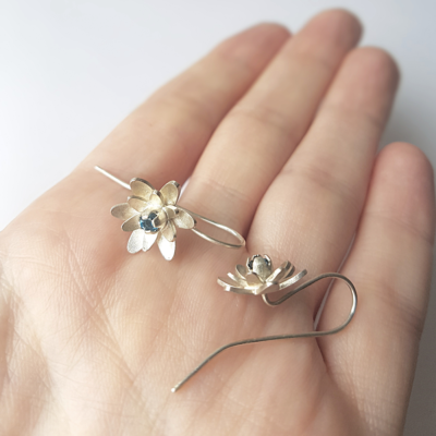 Unique Handmade silver earrings with blue topaz on a the palm.