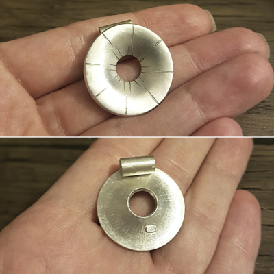 Handmade Donut Pendant Necklace in clean recycled sterling silver from the front and back on the palm.